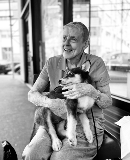 black and white photo of woman sitting down holding husky