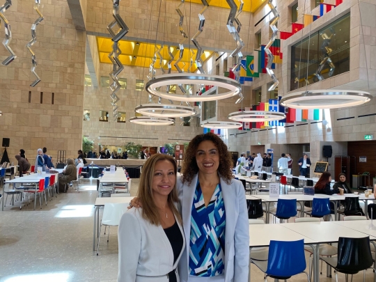 Two women standing together in atrium